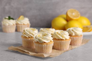 Photo of Delicious cupcakes with white cream and lemon zest on gray marble table, closeup