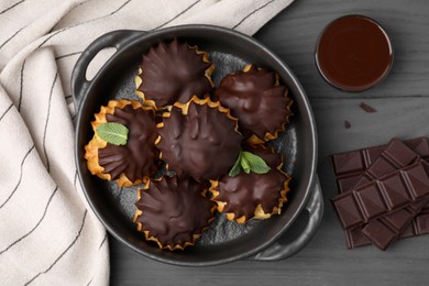 Delicious profiteroles with chocolate and mint on grey wooden table, flat lay