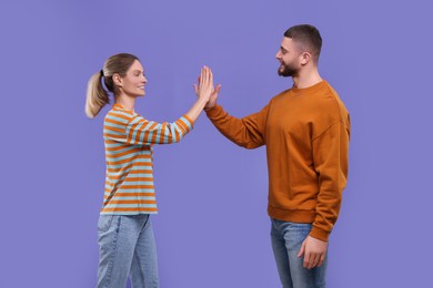 Happy couple giving high five on purple background