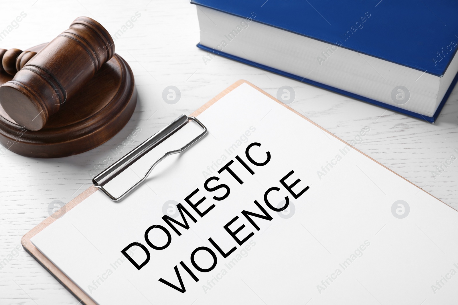 Photo of Clipboard with words DOMESTIC VIOLENCE and gavel on white wooden table, closeup