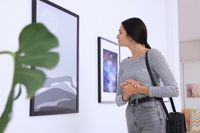Photo of Thoughtful young woman at exhibition in art gallery