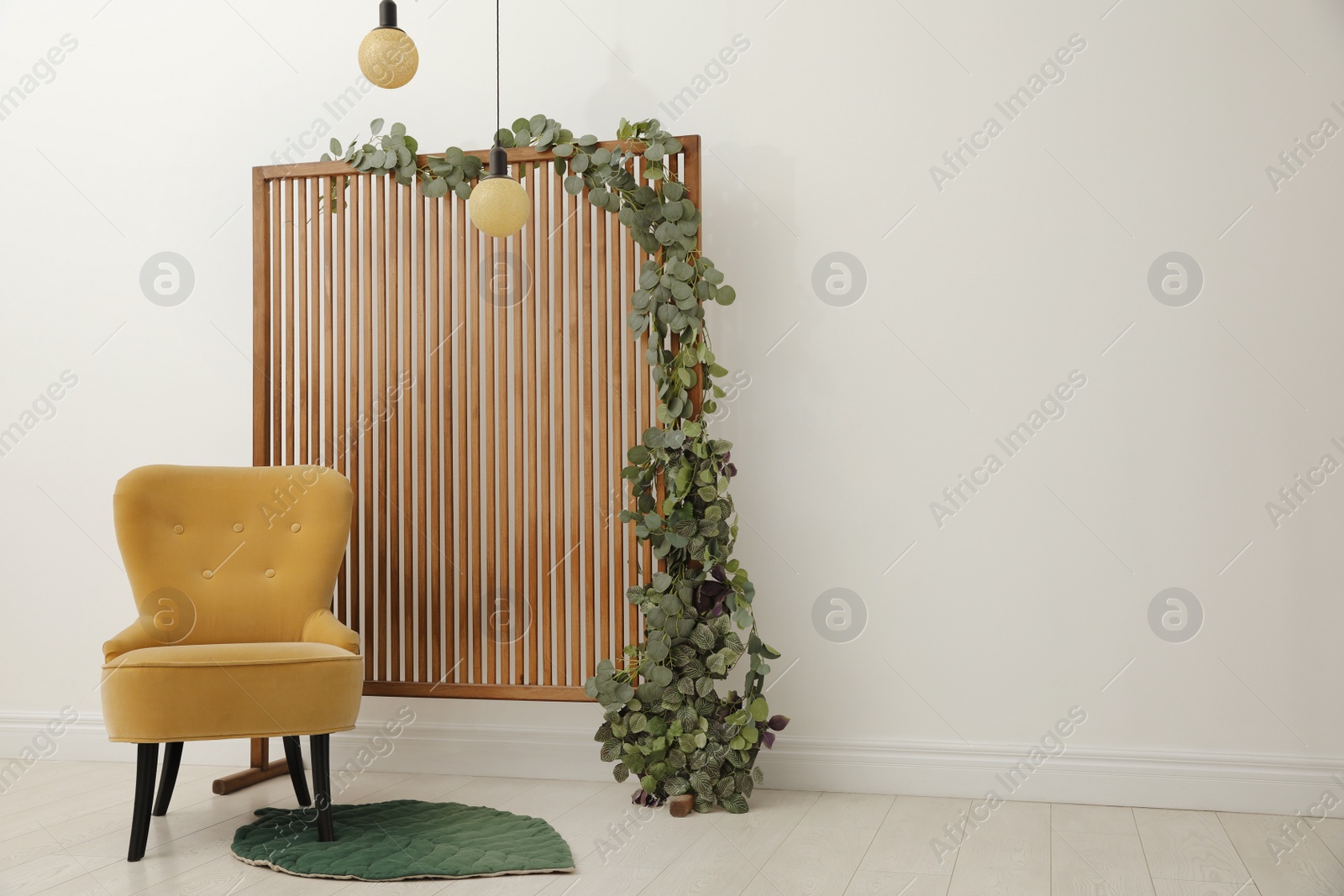 Photo of Stylish photo zone with wooden screen, floral decor and comfortable armchair indoors. Space for text