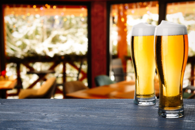 Image of Fresh cold beer on wooden table in pub, space for text