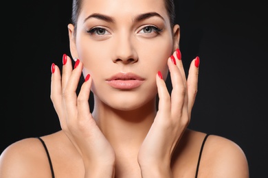 Beautiful young woman with bright manicure on black background, closeup. Nail polish trends