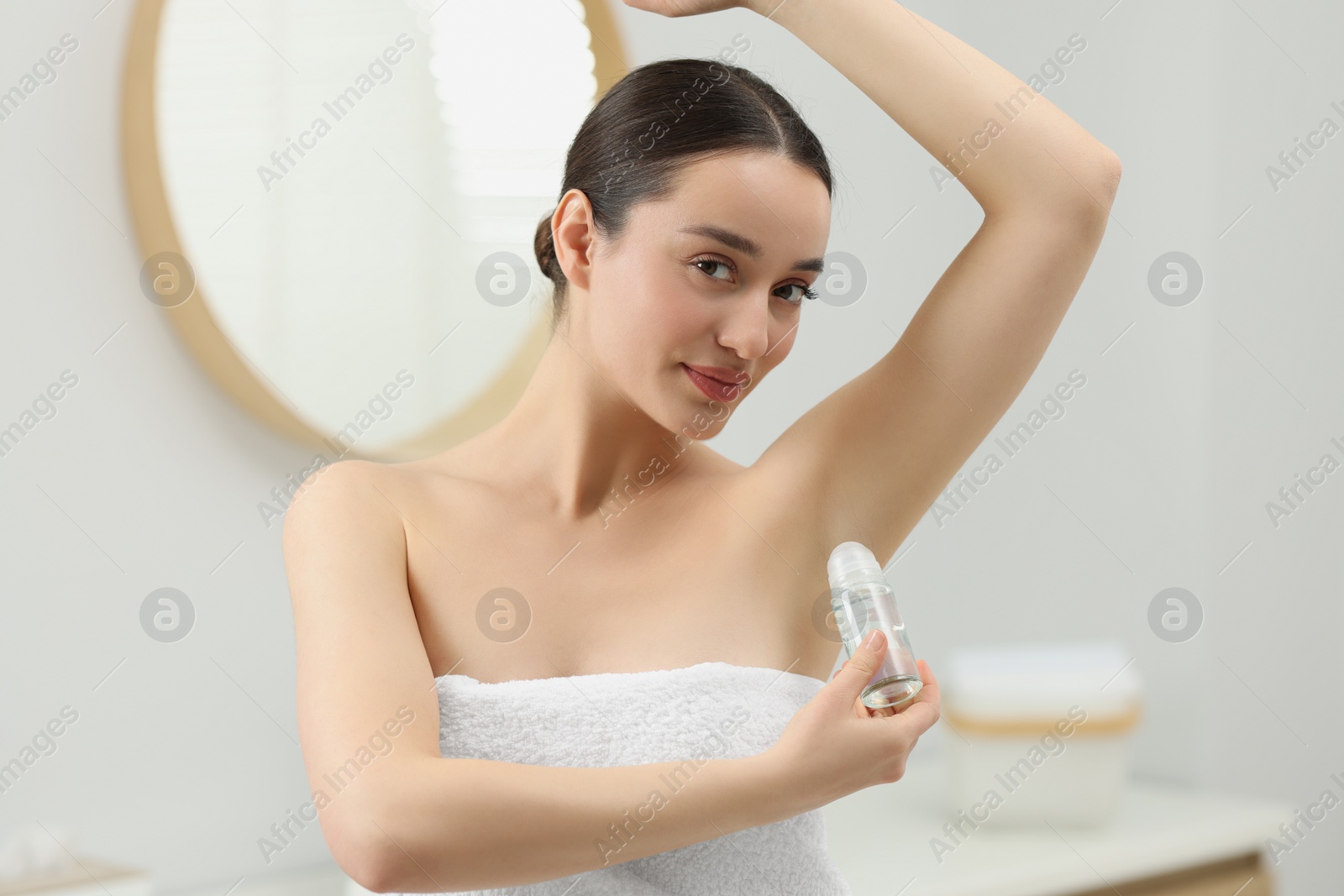 Photo of Beautiful young woman applying deodorant in bathroom