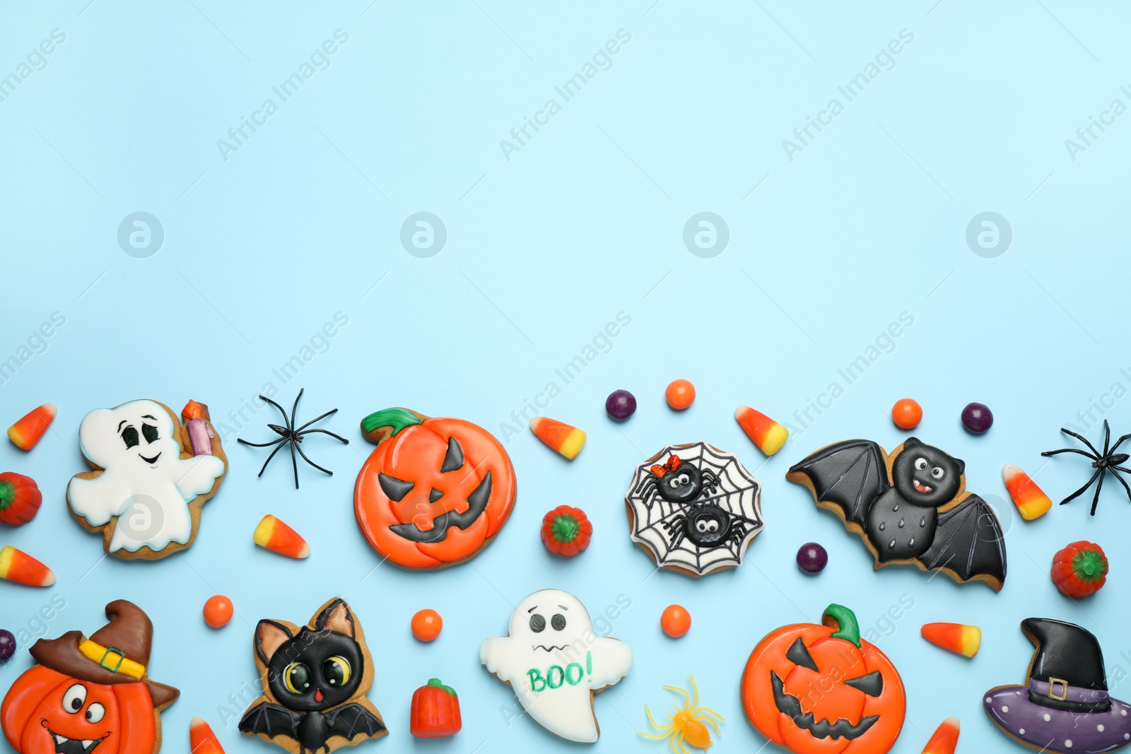 Photo of Tasty cookies and sweets for Halloween party on light blue background, flat lay. Space for text