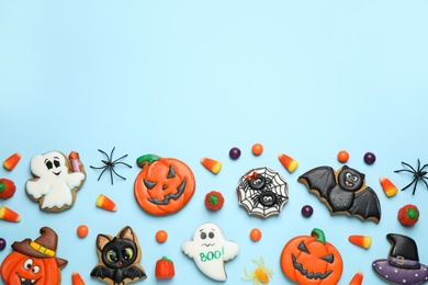 Tasty cookies and sweets for Halloween party on light blue background, flat lay. Space for text