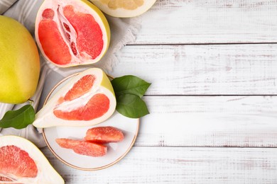 Photo of Tasty pomelo fruits on white wooden table, flat lay. Space for text