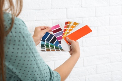 Photo of Female interior designer with color palette samples near brick wall, closeup