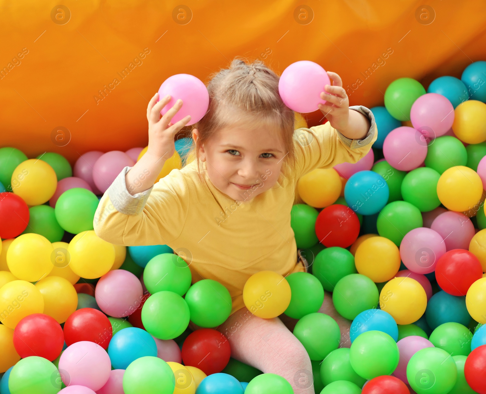 Photo of Cute little child playing in ball pit at indoor amusement park