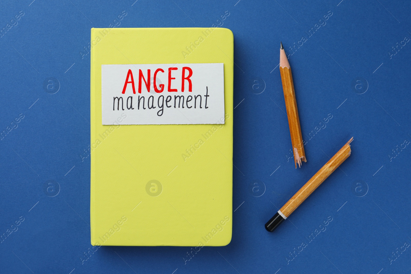 Photo of Notebook with words Anger Management and broken pencil on blue background, flat lay