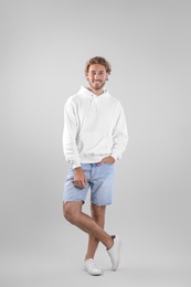 Full length portrait of man in hoodie sweater on light background. Space for design