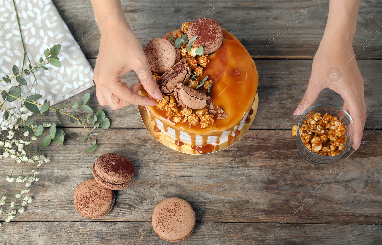 Photo of Young woman decorating delicious caramel cake at table