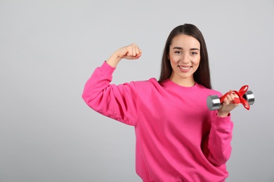 Photo of Woman with dumbbell as symbol of girl power on light grey background. 8 March concept