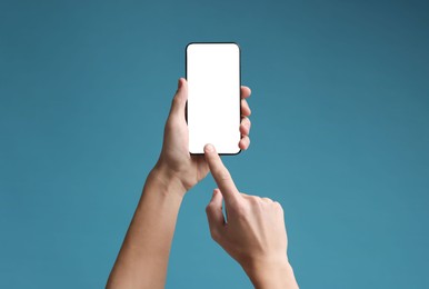 Photo of Man using smartphone with blank screen on light blue background, closeup. Mockup for design