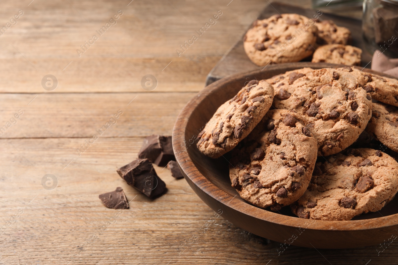 Photo of Delicious chocolate chip cookies on wooden table. Space for text