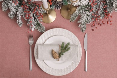 Photo of Festive place setting with beautiful dishware, cutlery and cone for Christmas dinner on pink tablecloth, flat lay
