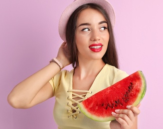 Beautiful young woman posing with watermelon on color background