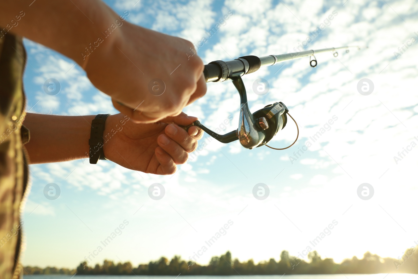 Photo of Fisherman with rod fishing under blue sky, closeup