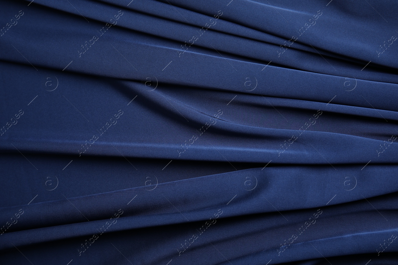 Photo of Crumpled dark blue silk fabric as background, top view