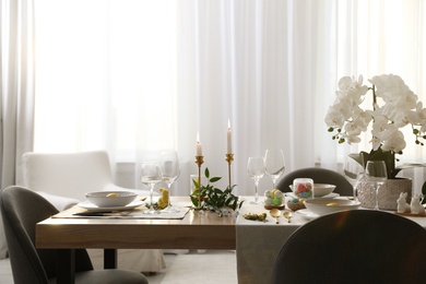 Photo of Beautiful Easter table setting with orchid flowers indoors