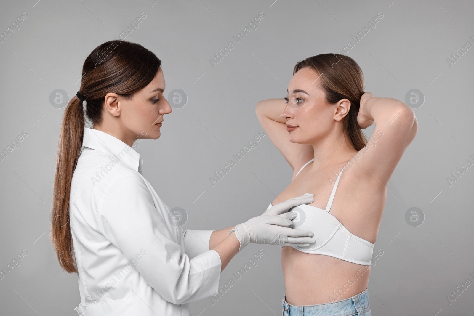 Photo of Mammologist checking woman's breast on gray background