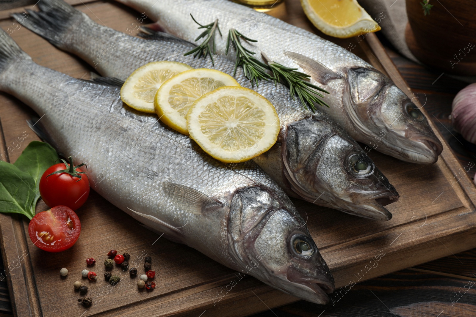 Photo of Sea bass fish and ingredients on wooden table, closeup