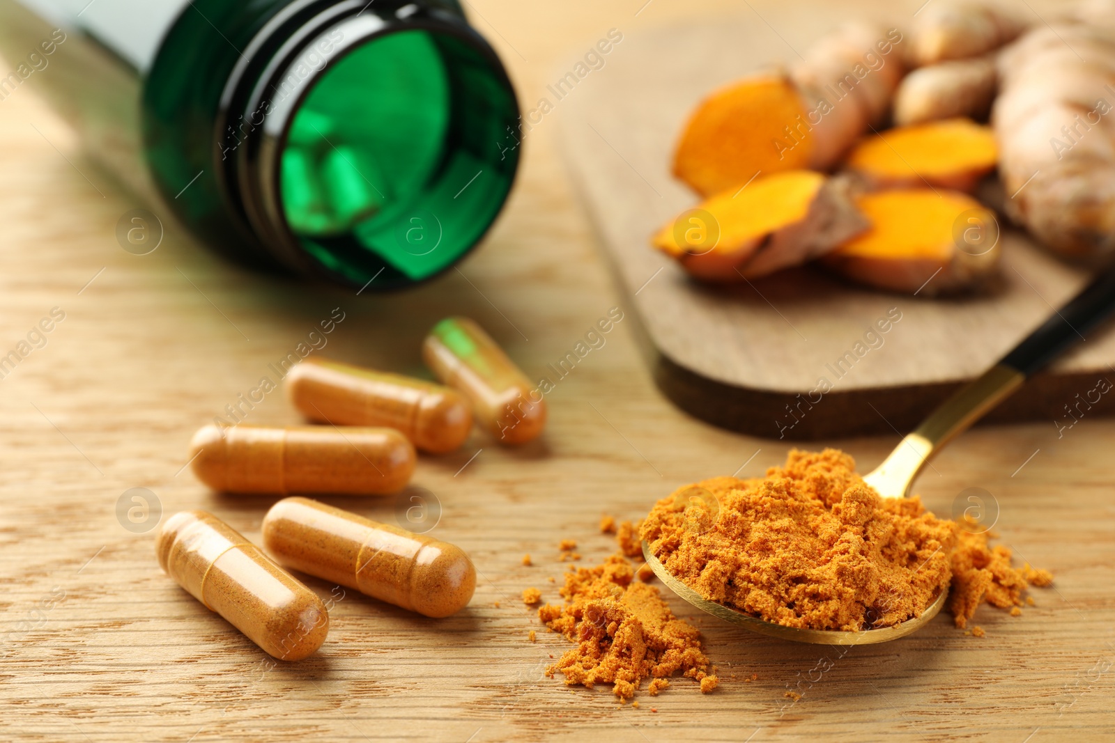 Photo of Aromatic turmeric powder and pills on wooden table, closeup