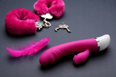 Vaginal vibrator, feather and handcuffs on black background. Sex toys