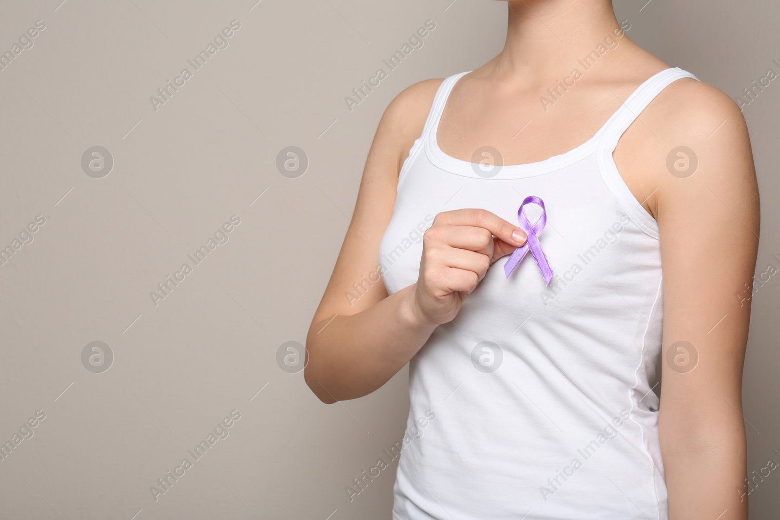 Photo of Woman holding purple ribbon on grey background, closeup with space for text. Domestic violence awareness