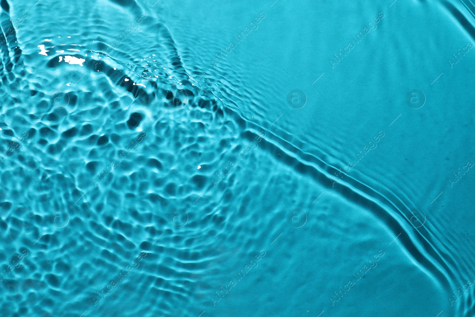 Photo of Rippled surface of clear water on light blue background, top view