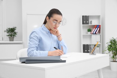 Photo of Young female intern working at table in office