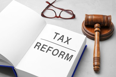 Image of Book with text TAX REFORM, gavel and glasses on light grey table
