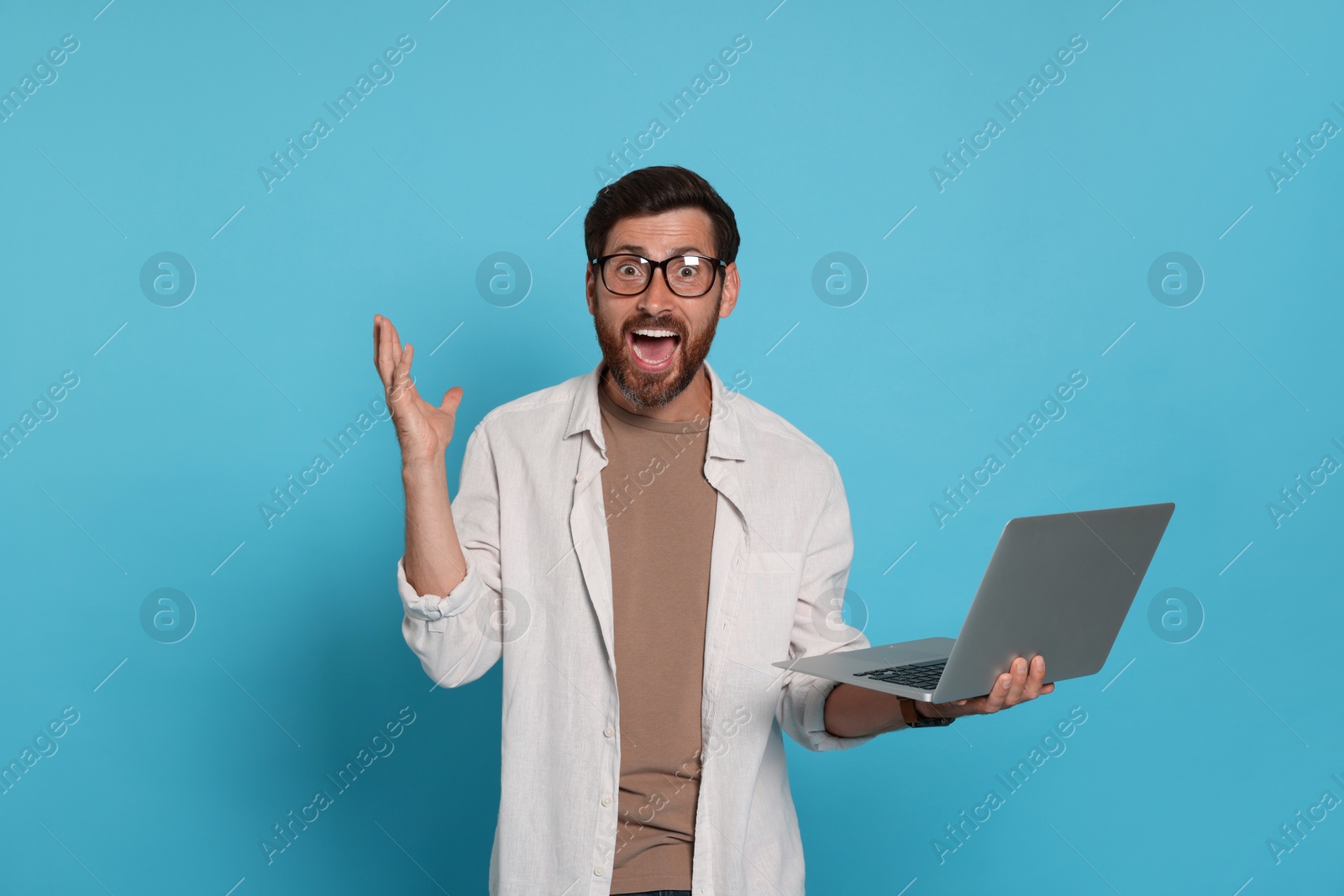 Photo of Emotional man with laptop on light blue background