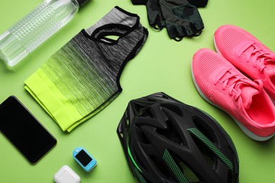 Photo of Flat lay composition with different cycling accessories and clothes on green background