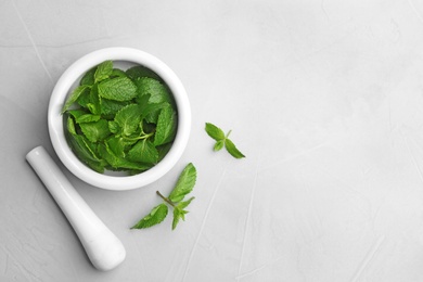 Fresh mint with mortar and pestle on grey background, flat lay. Space for text