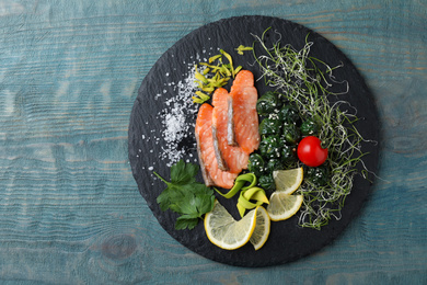 Photo of Tasty salmon with spinach on blue wooden table, top view