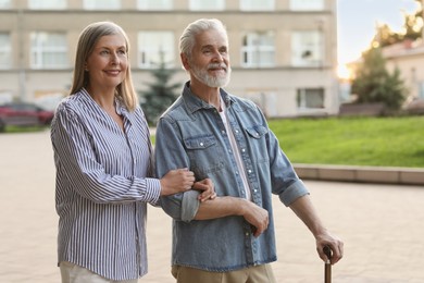 Photo of Senior man with walking cane and mature woman outdoors