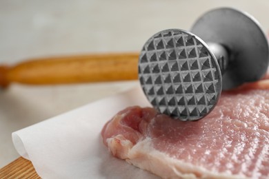 Photo of Cooking schnitzel. Raw pork chops and meat mallet on wooden board, closeup
