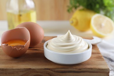 Photo of Fresh mayonnaise sauce in bowl and ingredients on table, closeup