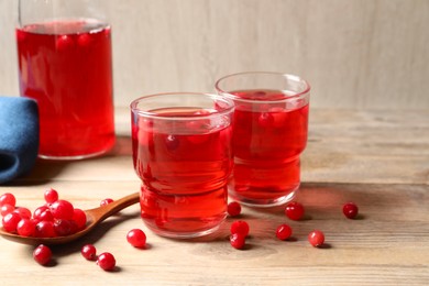 Tasty cranberry juice in glasses and fresh berries on wooden table, closeup