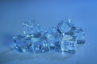 Photo of Pile of crystal clear ice cubes on color background