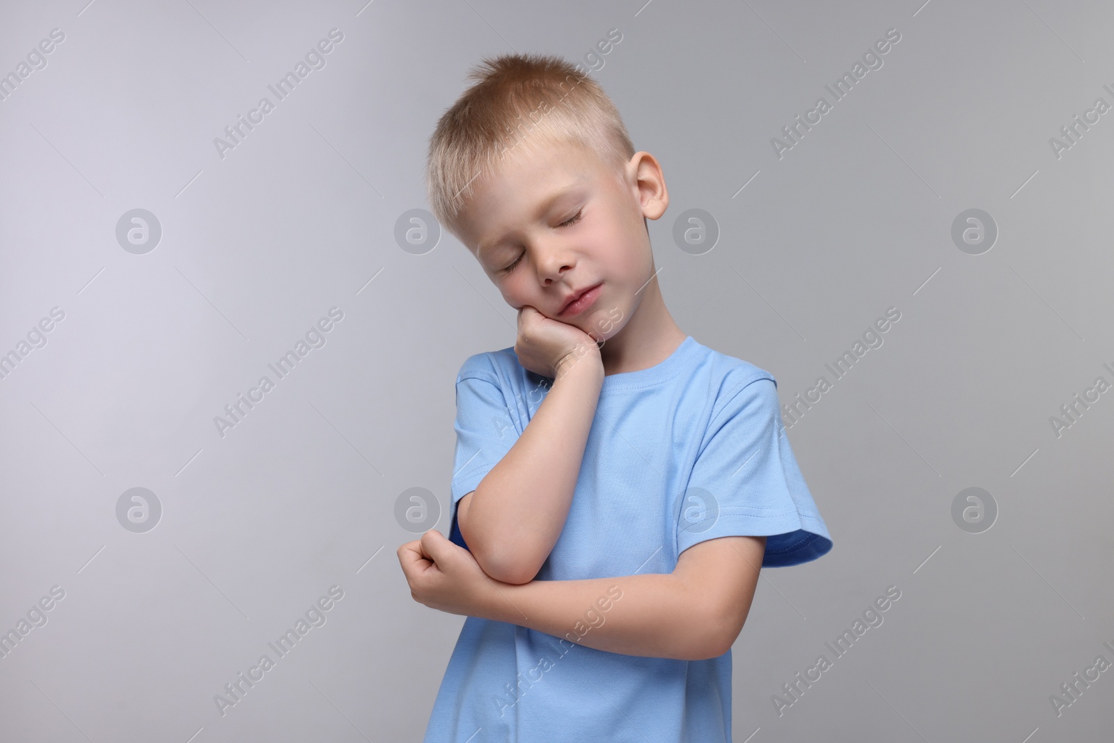 Photo of Sleepy boy on light grey background. Insomnia problem