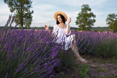 Beautiful young woman sitting in lavender field