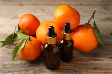 Bottles of tangerine essential oil and fresh fruits on wooden table