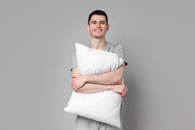 Photo of Happy man in pyjama holding pillow on grey background