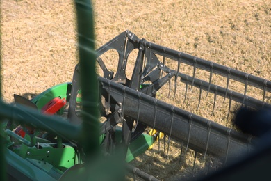 Photo of Modern combine harvester in agricultural field, closeup view of reel