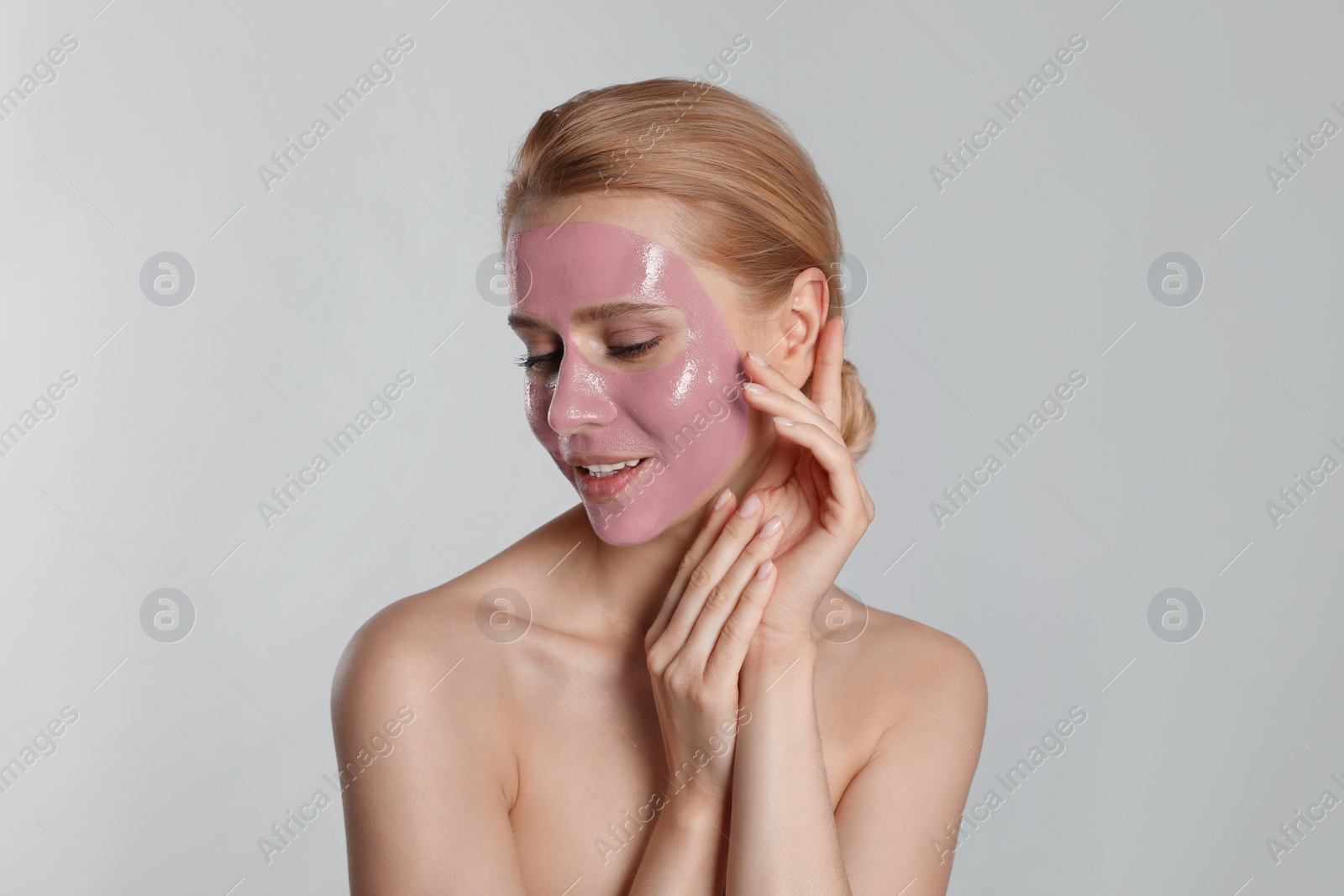 Photo of Young woman with pomegranate face mask on light grey background