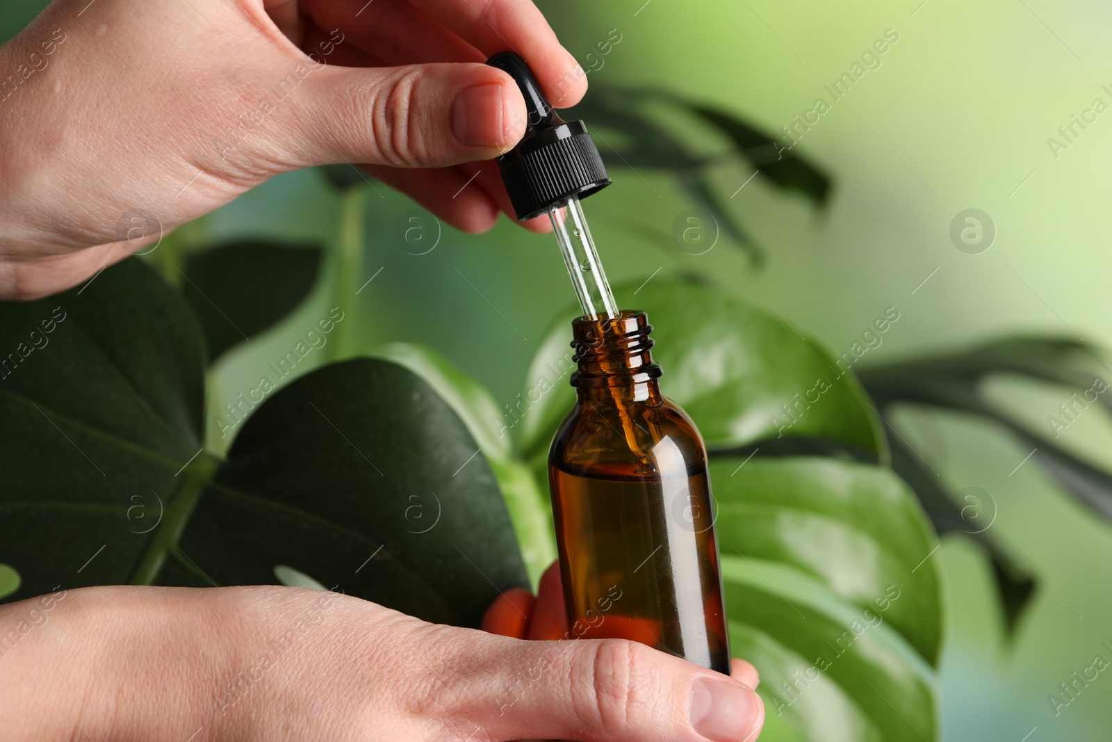 Photo of Woman with bottle of cosmetic serum and dropper on green background, closeup