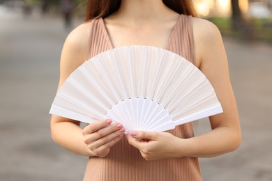 Photo of Woman with white hand fan outdoors, closeup